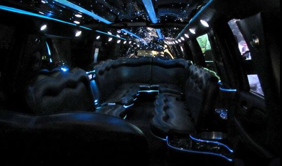 Hummer limo interior with black leather seating, blue accent lights, and a starry ceiling effect.