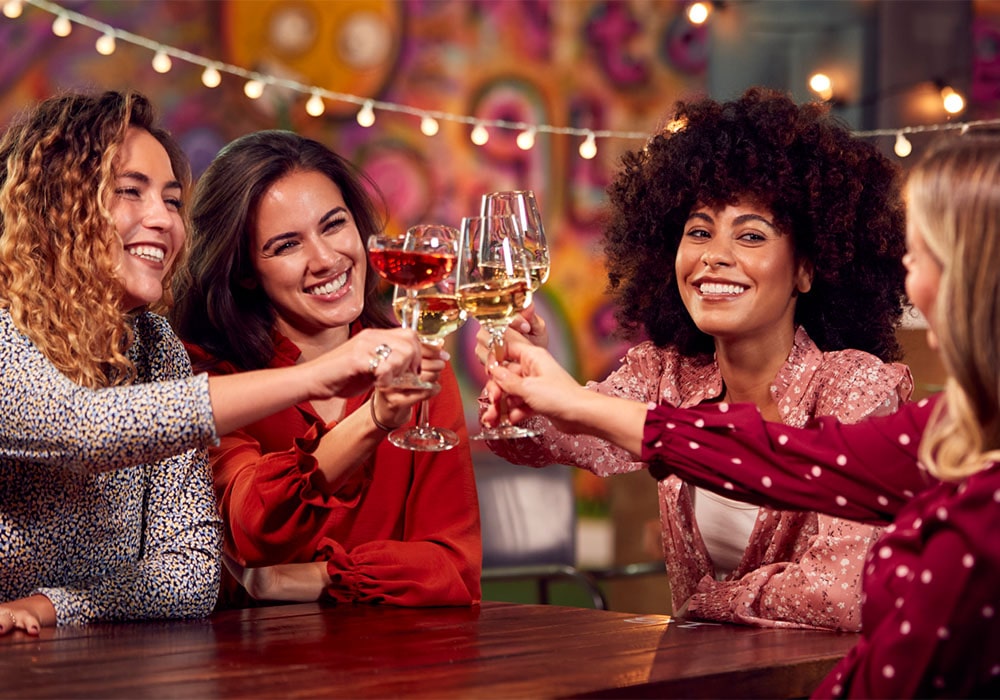 Four joyful women toasting with wine in a wine tasting room.