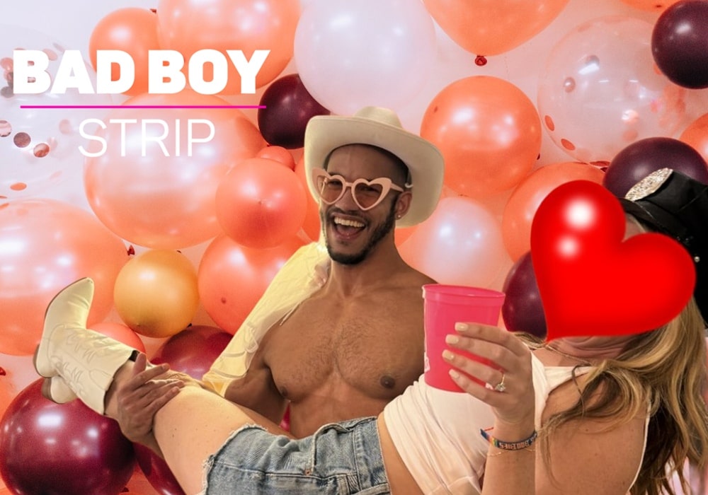 Shirtless man in heart-shaped sunglasses and a cowboy hat holding a woman in a party setting filled with festive balloons.