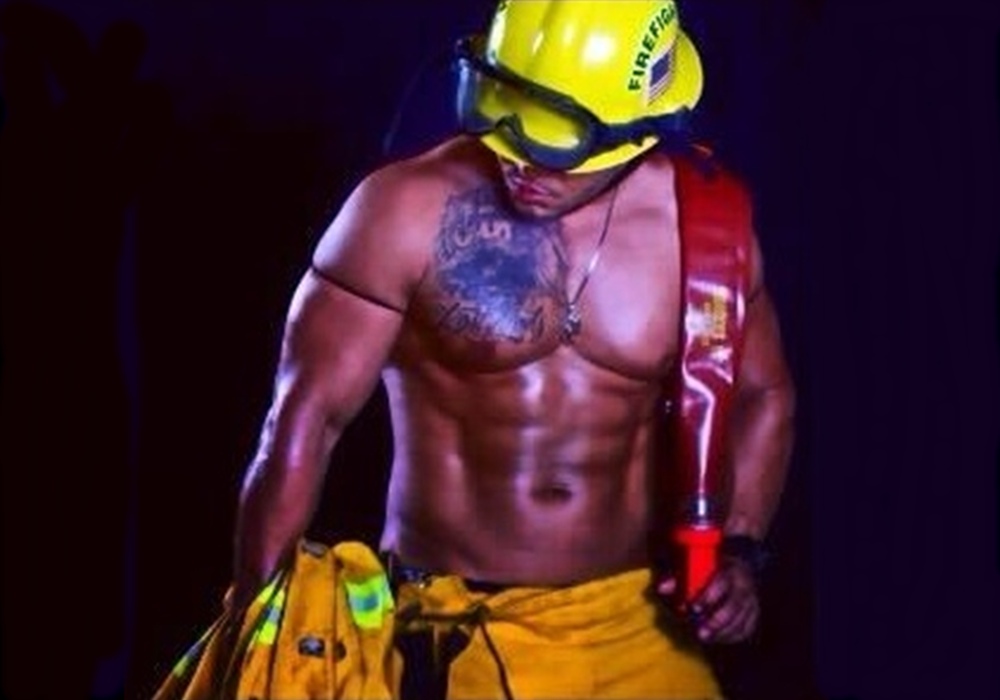 Muscular man in firefighter-themed outfit, posing for the camera.