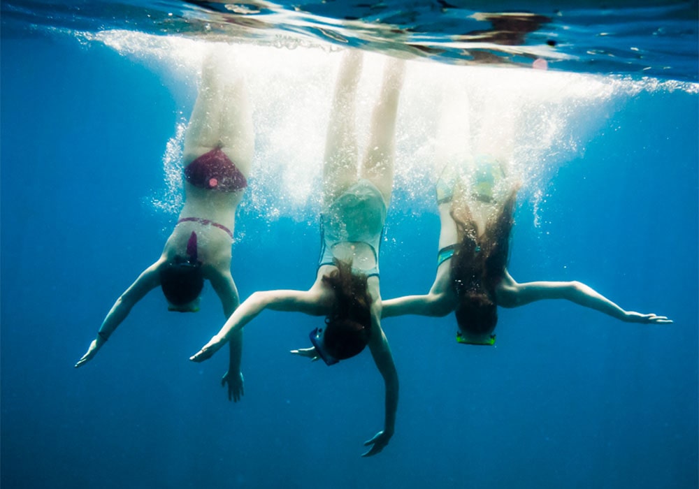 Three woman scuba diving in the ocean.