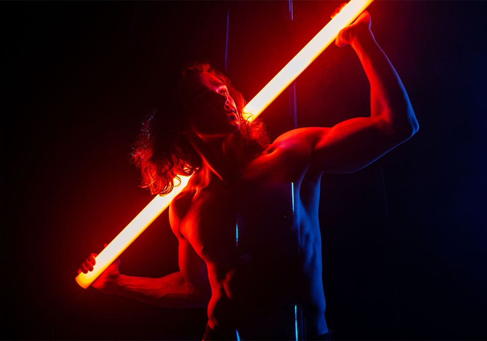 Young muscular shirtless guy posing with a neon tube.
